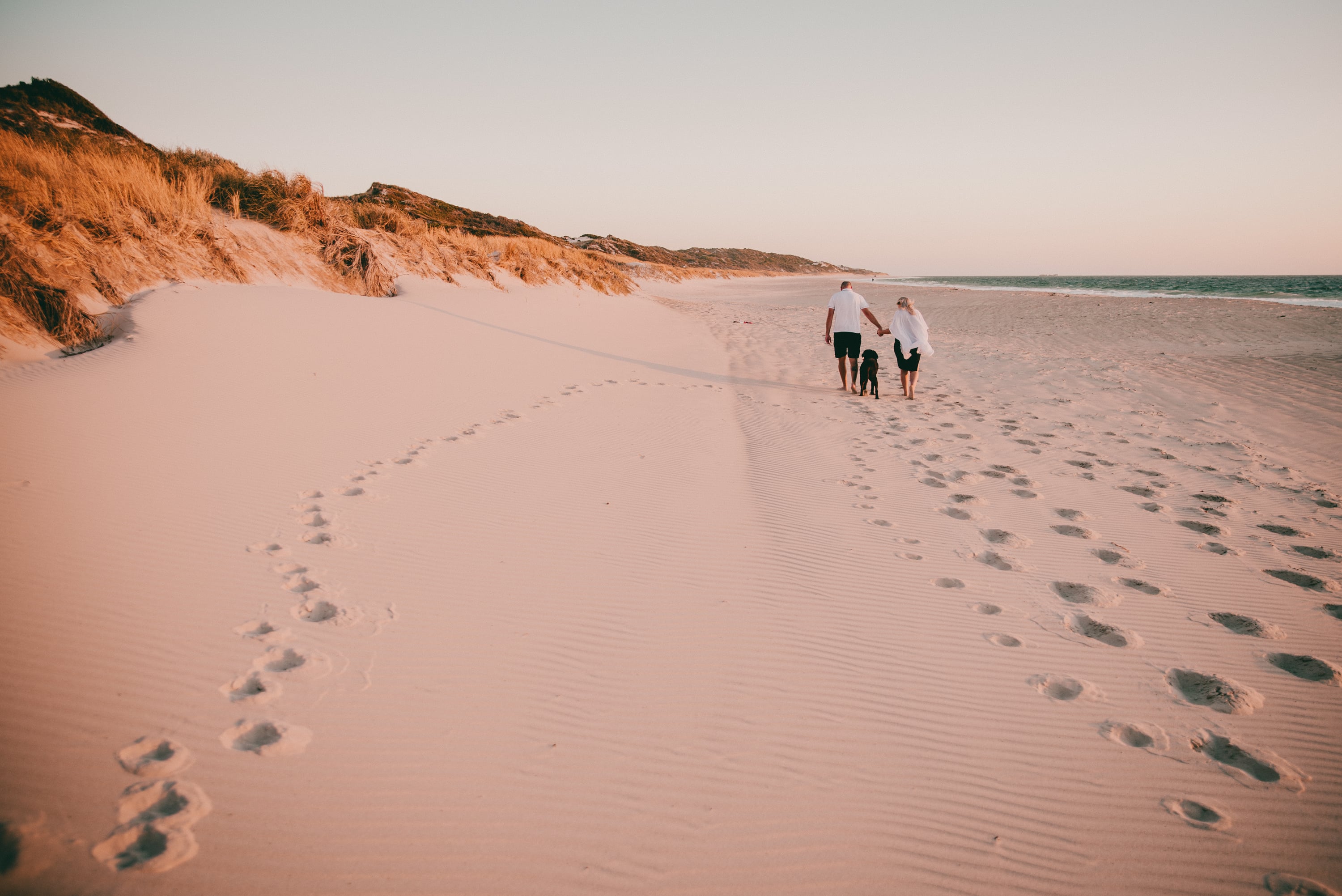 Family walking along a sweeping beach at golden hour